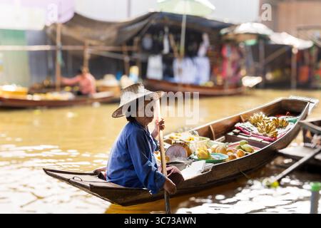 Mercato galleggiante di Damnoen Saduak, Bangkok, Thailandia - tradizionale venditore thailandese che vende frutta tropicale da una barca di legno. Foto Stock