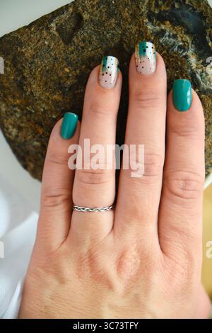 Mani femminili con design a chiodo verde. Foto Stock