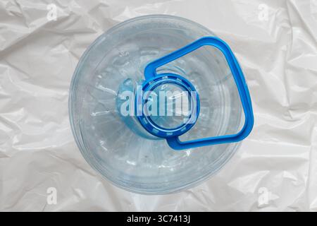 Flacone in plastica da 5 litri con manico blu sulla parte superiore su sfondo bianco in polietilene, vista dall'alto Foto Stock