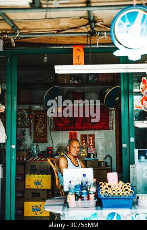 Minimarket colorato a lato della strada a Hong Kong che vende spuntini, bevande e prodotti di tutti i giorni sotto una tenda luminosa. Foto Stock