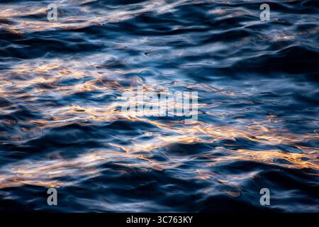 Al crepuscolo, i raggi del sole si illuminano sulle punte delle onde in questo scatto con otturatore lento. LAC Leman, Svizzera. Foto Stock