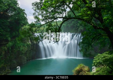 Splendida cascata Shifen nel quartiere di Pingxi, nuova Taipei, circondata da vegetazione lussureggiante, catturata in una giornata estiva nel 2010 con cieli azzurri. Foto Stock
