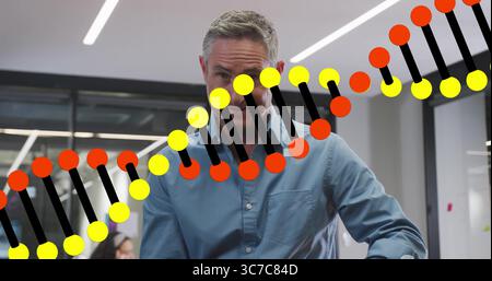 Uomo gestante in camicia blu che spiega la grafica a doppia elica del DNA in ufficio, con monitor per computer Foto Stock