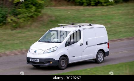 Milton Keynes,Bucks,UK - 1 agosto 2025: Furgone elettrico Nissan e-nv200 2018 bianco che guida su una strada britannica Foto Stock