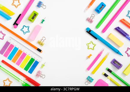 Layout creativo realizzato con cancelleria colorata al neon su sfondo bianco. Spazio per il testo Foto Stock
