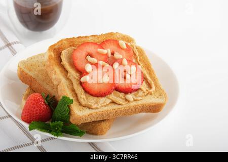 Panino dolce con fragole e burro di arachidi su un piatto. Foto Stock