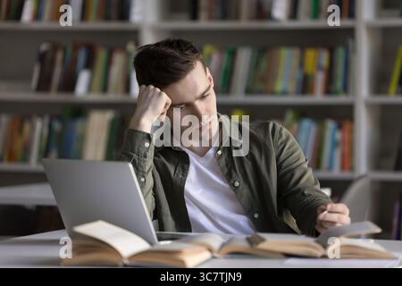 Giovane studente universitario serio che pensa alla soluzione difficile del problema Foto Stock