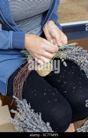 Donna che lega steli di lavanda per ghirlanda fatta a mano Foto Stock