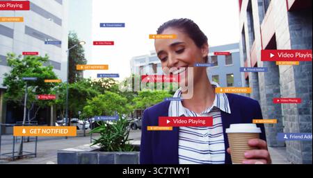 Donna sorridente che indossa un blazer che tiene in mano il caffè camminando nella piazza della città con sovrapposizioni digitali e spazio fotocopie Foto Stock