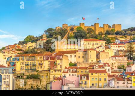 Vista panoramica del castello di São Jorge e degli edifici colorati di Alfama, Lisbona, Portogallo, durante l'ora d'oro, con cieli limpidi e una calda luce serale. Foto Stock