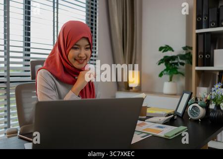 una dipendente di un'azienda musulmana lavora in una grande organizzazione finanziaria, una donna imprenditrice musulmana sta esaminando i documenti finanziari della sua azienda, il mercato Foto Stock