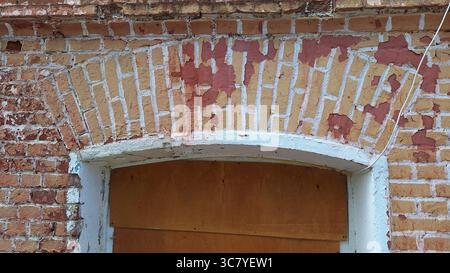 Arcata in mattoni con vernice sbucciata sopra la porta coperta Foto Stock