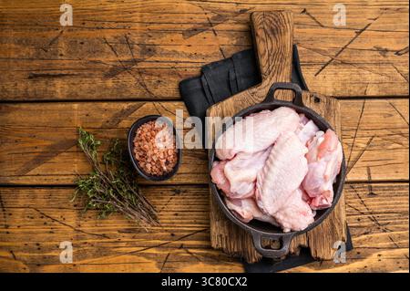 Succose ali ali di pollo crude, un ingrediente versatile perfetto per friggere, cuocere o grigliare alla perfezione. sfondo in legno. vista dall'alto. Foto Stock