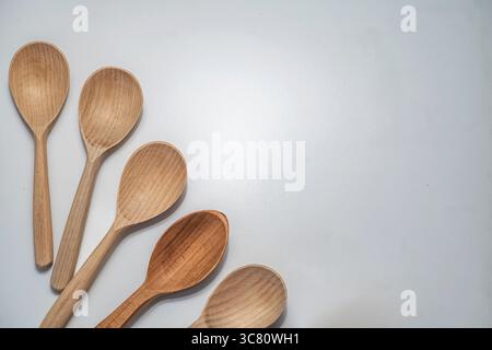 Cinque cucchiai di legno disposti su sfondo bianco. Utensili da cucina rustici e naturali per cucinare, servire e uno stile di vita ecologico. Foto Stock