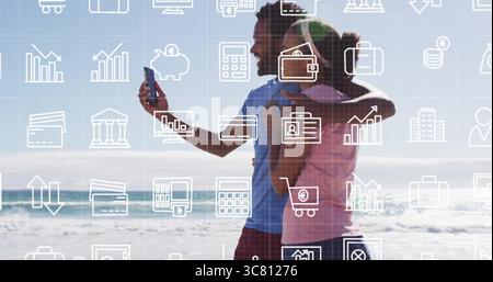 Coppia che scatta selfie sulla spiaggia sabbiosa, con smartphone e icone aziendali sovrapposte e spazio di copia Foto Stock