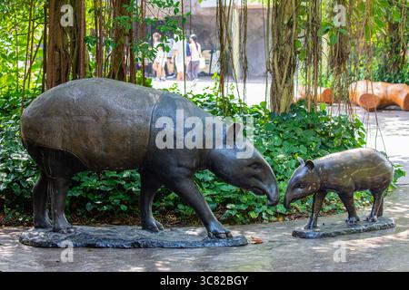 Singapore 21 giugno 2025: Il tapir malese Sculpture (Tapirus indicus) con vitello di fronte al Rainforest Wild ASIA, il quinto zoo di Singapore Foto Stock