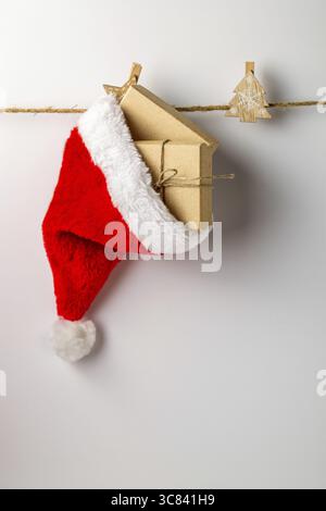Cappello di Babbo Natale con regali appesi su una corda su sfondo bianco Foto Stock
