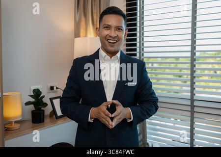 ritratto di un uomo d'affari di successo che guarda la fotocamera e sorride all'interno di un ufficio moderno, un leader aziendale sorridente e sicuro che guarda la fotocamera, un uomo d'affari felice Foto Stock