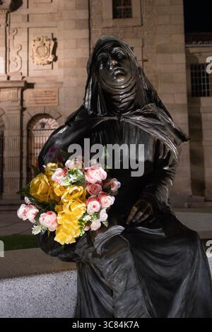 Immagine notturna della scultura di Santa Teresa con un mazzo di fiori colorati in primo piano con la Basilica di Santa Teresa sullo sfondo Foto Stock