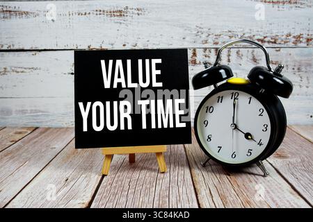 Valuta il tuo testo con il cavalletto e la sveglia su sfondo in legno Foto Stock