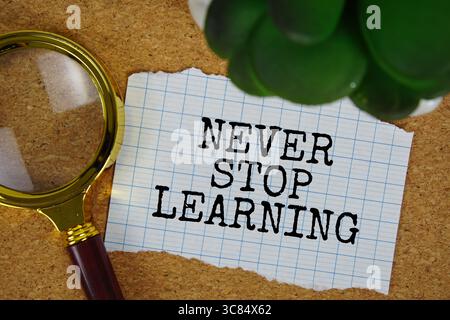 Non smettere mai di imparare testo scritto su carta con lente d'ingrandimento Foto Stock
