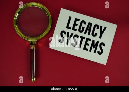 Testo dei sistemi legacy scritto su carta con lente d'ingrandimento Foto Stock
