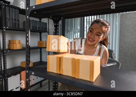 un imballatore controlla le condizioni di un pacco prima che venga consegnato a un cliente, un proprietario di una piccola impresa ispeziona le scatole in un magazzino o in un magazzino Foto Stock