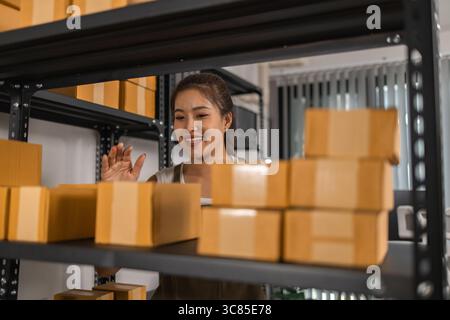 un imballatore controlla le condizioni di un pacco prima che venga consegnato a un cliente, un proprietario di una piccola impresa ispeziona le scatole in un magazzino o in un magazzino Foto Stock