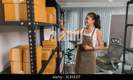 un imballatore controlla le condizioni di un pacco prima che venga consegnato a un cliente, un proprietario di una piccola impresa ispeziona le scatole in un magazzino o in un magazzino Foto Stock