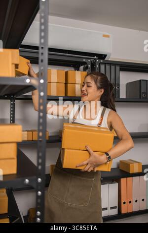 un imballatore controlla le condizioni di un pacco prima che venga consegnato a un cliente, un proprietario di una piccola impresa ispeziona le scatole in un magazzino o in un magazzino Foto Stock