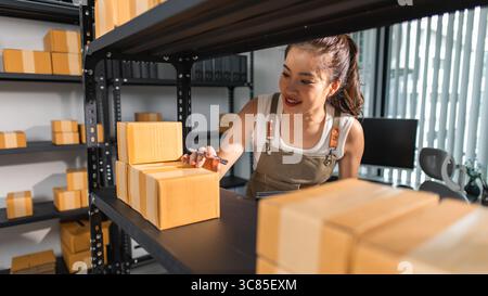 un imballatore controlla le condizioni di un pacco prima che venga consegnato a un cliente, un proprietario di una piccola impresa ispeziona le scatole in un magazzino o in un magazzino Foto Stock