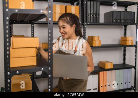 un imballatore controlla le condizioni di un pacco prima che venga consegnato a un cliente, un proprietario di una piccola impresa ispeziona le scatole in un magazzino o in un magazzino Foto Stock