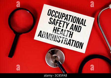 Testo della Occupational Safety and Health Administration scritto su carta con stetoscopio su sfondo rosso Foto Stock