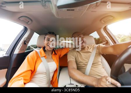 Coppia afroamericana eccitata che si diverte a guidare insieme, sorridendo e divertendosi Foto Stock