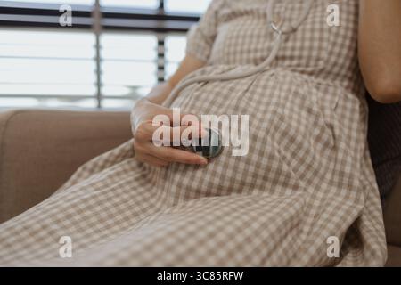 una madre incinta si sta rilassando su un divano in casa sua, la gravidanza di una donna, la famiglia, una donna era molto felice perché era incinta e presto sarebbe g Foto Stock