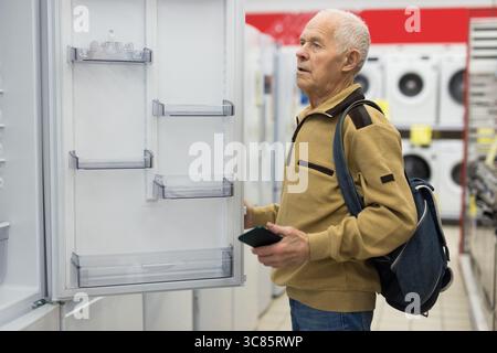 senor uomo pensionato acquistare frigorifero in showroom di elettrodomestici negozio Foto Stock