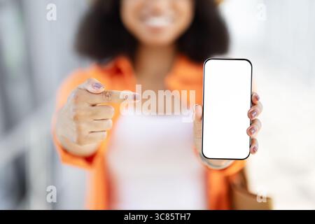 Giovane donna nera che punta allo smartphone con schermo vuoto Foto Stock