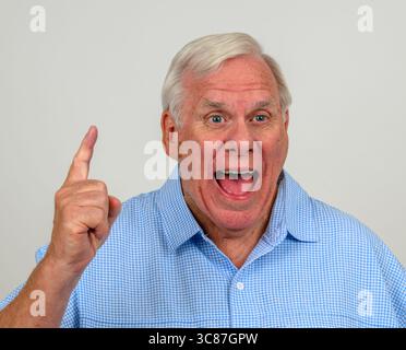 Uomo anziano che indossa una camicia a scacchi blu e bianca che esulta con un solo dito indice Foto Stock