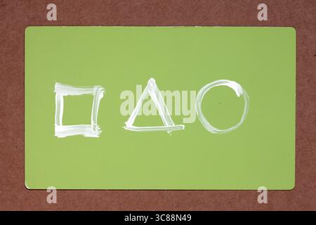 design minimalista con tre forme geometriche bianche: quadrate, triangolari e circolari disposte orizzontalmente su sfondo rettangolare verde chiaro Foto Stock