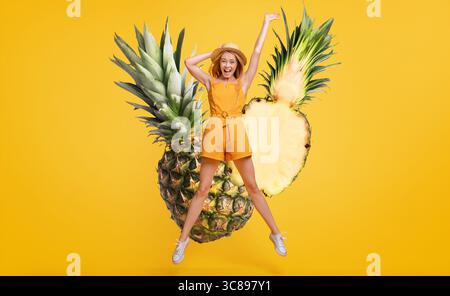 Donna gioiosa in abito giallo che si diverte con un fondo di frutta tropicale Foto Stock