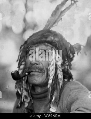 Ernest J Rawleigh - Un uomo delle prime Nazioni con una pipa in bocca da un villaggio sconosciuto in Ontario, Canada - tra il 1915 e il 1925 circa Foto Stock