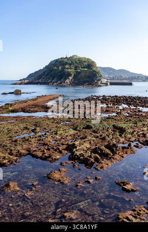 Vista dell'isola di Santa Clara dalla spiaggia di la Concha a San Sebastian, in Spagna, in una giornata limpida, con formazioni rocciose e l'oceano. Foto Stock