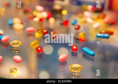 Compresse e capsule multicolore su una superficie di vetro. Medicina Foto Stock