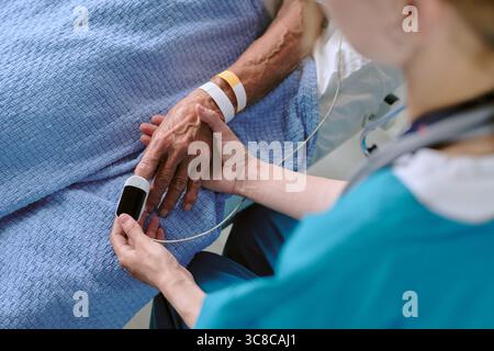 Uomo Nero di mezza età giacente nel letto di ospedale sottoposto a test di pulsossimetria Foto Stock