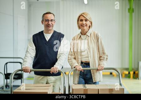Ritratto dell'uomo e della donna caucasica di mezza età sorridenti mentre si spostano le scatole Foto Stock
