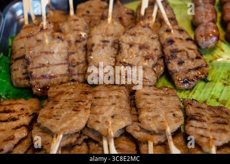 Carne tradizionale su bastoncino, satay di maiale grigliato o moo ping in Thailandia. Il Moo ping e' un popolare spuntino di Street food in Thaland disponibile presso i mercati notturni Foto Stock