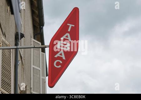 Cartellone rosso a forma di diamante inclinato con la parola tabac bianco e neon sopra un negozio a Saint-Céré Lot Occitanie, Francia meridionale. Foto Stock