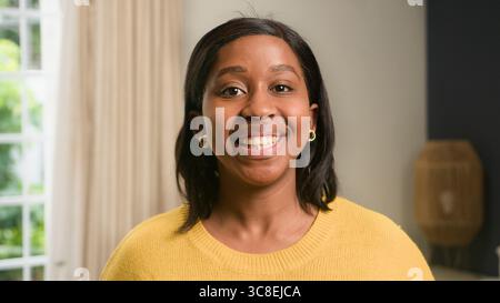 Giovane donna sorridente che posa in interni in uno spazio abitativo luminoso e accogliente Foto Stock