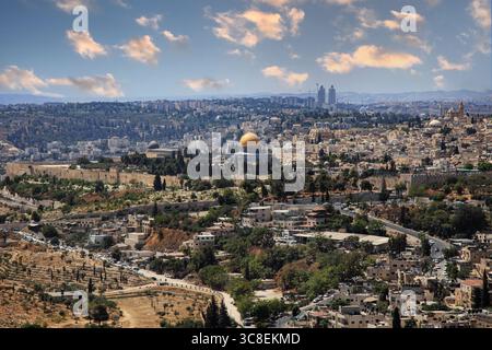 Vista panoramica di Gerusalemme con l'iconica cupola dorata, gli antichi edifici in pietra e un suggestivo skyline sotto un cielo parzialmente nuvoloso. Foto Stock