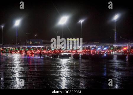 Vista notturna del valico di frontiera di San Ysidro, Tijuana, un popolare punto di migrazione, con auto allineate al confine tra Stati Uniti e Messico Foto Stock